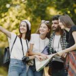 Young friends exploring a park with a map, smiling and enjoying the outdoors., tags: und - pexel