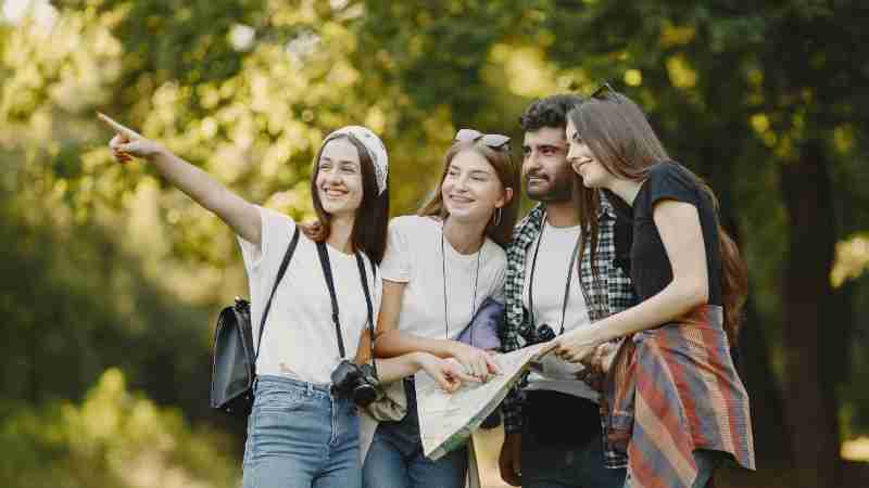 Young friends exploring a park with a map, smiling and enjoying the outdoors., tags: und - pexel