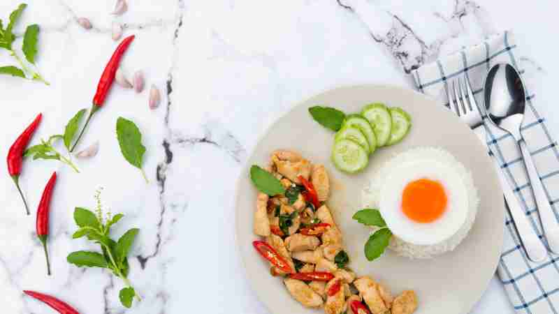 Delicious Thai basil chicken dish with rice and fried egg garnished with chili and cucumber., tags: mediterrane für - pexel